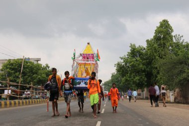 GHAZIABAD, UTTAR PRADESH, INDIA - Temmuz 2019: Kanwar 'ı omuzlarında taşıyan bir Hindu müridi, her yıl sokaklarda çıplak ayakla kutsal Ganga suyuyla kanwar yatını icra ediyor..