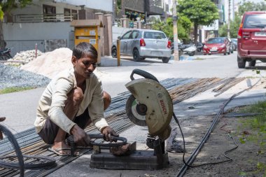 VRINDAVAN, UTTAR PRADESH, INDIA - AĞUSTOS 2021: Krishna Janmashtami, Vrindavan caddesinde oturan ve çeliği dairesel testereyle kesen Hintli adam portresi