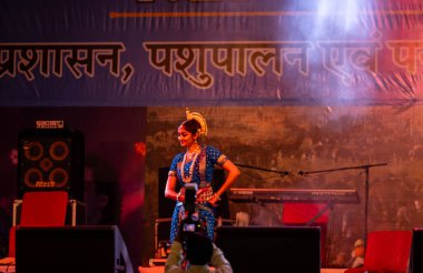 Puşkar, Rajasthan, Hindistan - 10 Kasım 2024: Pushkar fuarı sırasında geleneksel renkli etnik elbise ve mücevherlerle klasik dans yapan kadın sanatçı. Seçici odak.