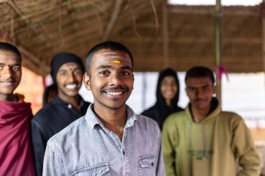 Bir grup gülümseyen genç adam binanın içinde duruyor.