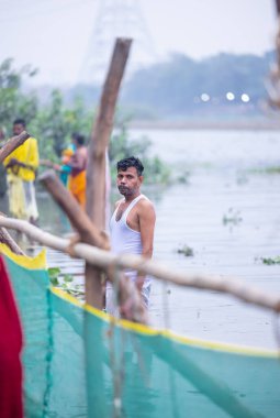 Gaziabad, Uttar Pradesh, Hindistan - 27 Ekim 2025: Chhas Puja, tanımlanamayan Hindu erkek dindarların portresi gün batımında Lord Sun 'a ibadet etmek için nehirde durarak Chhas ayinlerini gerçekleştiriyor..