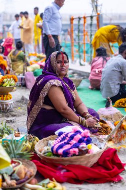Gaziabad, Uttar Pradesh, Hindistan - 27 Ekim 2025: Chhas Puja, tanımlanamayan Hindu kadın dindar portresi gün batımında toprağa tapan lord güneşinin üzerinde oturarak Chhas ayinlerini gerçekleştiriyor..
