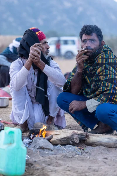 Puşkar, Rajasthan, Hindistan - 11 Kasım 2024: Geleneksel beyaz giysili rajasthani erkek portresi çöl panayırında renkli türbanla deve pazarında deve ticareti yaparken.