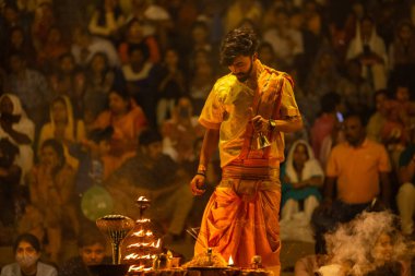 Varanasi, Uttar Pradesh, Hindistan - 21 Mart 2024: Ganga aarti, bir grup genç erkek rahip Assi Ghat 'ta geleneksel Hint ayinleri ile geleneksel elbise giyerek akşam üstü Ganga duası yapıyorlar..