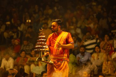 Varanasi, Uttar Pradesh, Hindistan - 21 Mart 2024: Ganga aarti, bir grup genç erkek rahip Assi Ghat 'ta geleneksel Hint ayinleri ile geleneksel elbise giyerek akşam üstü Ganga duası yapıyorlar..