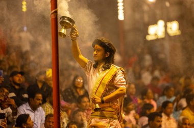 Varanasi, Uttar Pradesh, Hindistan - 21 Mart 2024: Ganga aarti, bir grup genç erkek rahip Assi Ghat 'ta geleneksel Hint ayinleri ile geleneksel elbise giyerek akşam üstü Ganga duası yapıyorlar..
