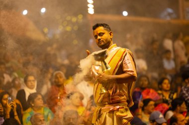 Varanasi, Uttar Pradesh, Hindistan - 21 Mart 2024: Ganga aarti, bir grup genç erkek rahip Assi Ghat 'ta geleneksel Hint ayinleri ile geleneksel elbise giyerek akşam üstü Ganga duası yapıyorlar..