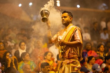 Varanasi, Uttar Pradesh, Hindistan - 21 Mart 2024: Ganga aarti, bir grup genç erkek rahip Assi Ghat 'ta geleneksel Hint ayinleri ile geleneksel elbise giyerek akşam üstü Ganga duası yapıyorlar..