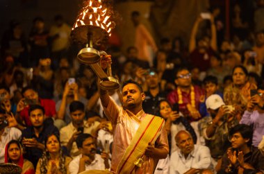 Varanasi, Uttar Pradesh, Hindistan - 21 Mart 2024: Ganga aarti, bir grup genç erkek rahip Assi Ghat 'ta geleneksel Hint ayinleri ile geleneksel elbise giyerek akşam üstü Ganga duası yapıyorlar..