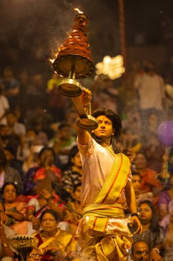 Varanasi, Uttar Pradesh, Hindistan - 21 Mart 2024: Ganga aarti, bir grup genç erkek rahip Assi Ghat 'ta geleneksel Hint ayinleri ile geleneksel elbise giyerek akşam üstü Ganga duası yapıyorlar..