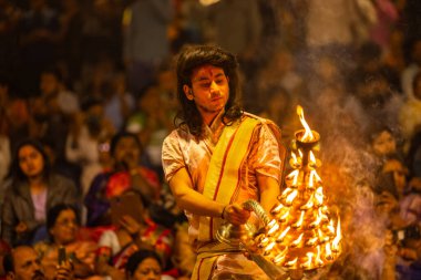 Varanasi, Uttar Pradesh, Hindistan - 21 Mart 2024: Ganga aarti, bir grup genç erkek rahip Assi Ghat 'ta geleneksel Hint ayinleri ile geleneksel elbise giyerek akşam üstü Ganga duası yapıyorlar..