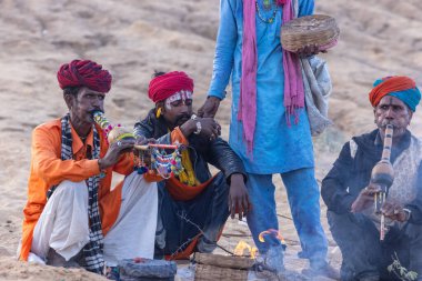 Puşkar, Rajasthan, Hindistan - 11 Kasım 2024: Geleneksel beyaz giysili rajasthani erkek portresi çöl panayırında renkli türbanla deve pazarında deve ticareti yaparken.