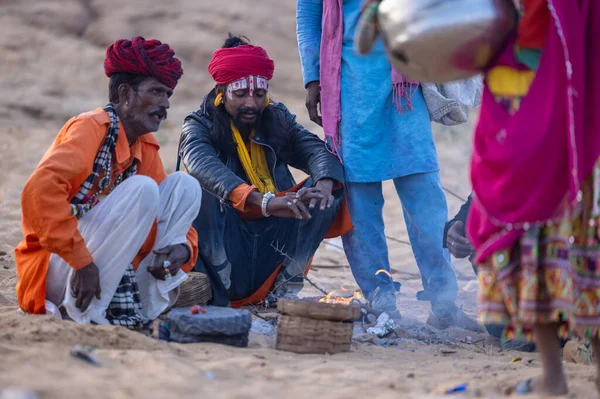 Puşkar, Rajasthan, Hindistan - 11 Kasım 2024: Geleneksel beyaz giysili rajasthani erkek portresi çöl panayırında renkli türbanla deve pazarında deve ticareti yaparken.