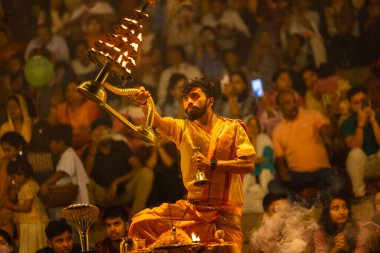 Varanasi, Uttar Pradesh, Hindistan - 21 Mart 2024: Ganga aarti, bir grup genç erkek rahip Assi Ghat 'ta geleneksel Hint ayinleri ile geleneksel elbise giyerek akşam üstü Ganga duası yapıyorlar..