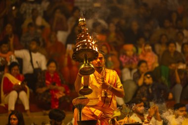 Varanasi, Uttar Pradesh, Hindistan - 21 Mart 2024: Ganga aarti, bir grup genç erkek rahip Assi Ghat 'ta geleneksel Hint ayinleri ile geleneksel elbise giyerek akşam üstü Ganga duası yapıyorlar..