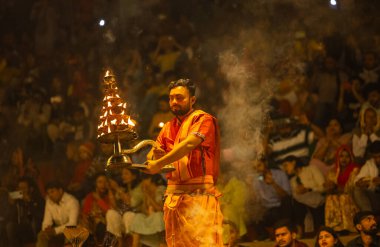 Varanasi, Uttar Pradesh, Hindistan - 21 Mart 2024: Ganga aarti, bir grup genç erkek rahip Assi Ghat 'ta geleneksel Hint ayinleri ile geleneksel elbise giyerek akşam üstü Ganga duası yapıyorlar..