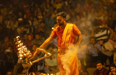 Varanasi, Uttar Pradesh, Hindistan - 21 Mart 2024: Ganga aarti, bir grup genç erkek rahip Assi Ghat 'ta geleneksel Hint ayinleri ile geleneksel elbise giyerek akşam üstü Ganga duası yapıyorlar..