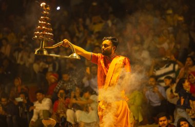 Varanasi, Uttar Pradesh, Hindistan - 21 Mart 2024: Ganga aarti, bir grup genç erkek rahip Assi Ghat 'ta geleneksel Hint ayinleri ile geleneksel elbise giyerek akşam üstü Ganga duası yapıyorlar..