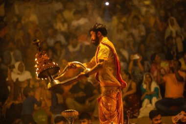 Varanasi, Uttar Pradesh, Hindistan - 21 Mart 2024: Ganga aarti, bir grup genç erkek rahip Assi Ghat 'ta geleneksel Hint ayinleri ile geleneksel elbise giyerek akşam üstü Ganga duası yapıyorlar..