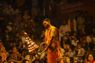 Varanasi, Uttar Pradesh, Hindistan - 21 Mart 2024: Ganga aarti, bir grup genç erkek rahip Assi Ghat 'ta geleneksel Hint ayinleri ile geleneksel elbise giyerek akşam üstü Ganga duası yapıyorlar..