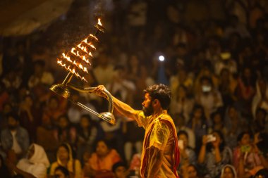 Varanasi, Uttar Pradesh, Hindistan - 21 Mart 2024: Ganga aarti, bir grup genç erkek rahip Assi Ghat 'ta geleneksel Hint ayinleri ile geleneksel elbise giyerek akşam üstü Ganga duası yapıyorlar..