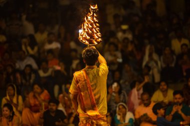 Varanasi, Uttar Pradesh, Hindistan - 21 Mart 2024: Ganga aarti, bir grup genç erkek rahip Assi Ghat 'ta geleneksel Hint ayinleri ile geleneksel elbise giyerek akşam üstü Ganga duası yapıyorlar..