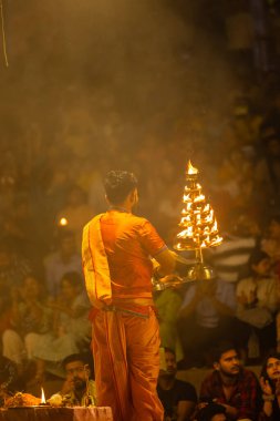Varanasi, Uttar Pradesh, Hindistan - 21 Mart 2024: Ganga aarti, bir grup genç erkek rahip Assi Ghat 'ta geleneksel Hint ayinleri ile geleneksel elbise giyerek akşam üstü Ganga duası yapıyorlar..