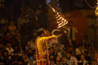 Varanasi, Uttar Pradesh, Hindistan - 21 Mart 2024: Ganga aarti, bir grup genç erkek rahip Assi Ghat 'ta geleneksel Hint ayinleri ile geleneksel elbise giyerek akşam üstü Ganga duası yapıyorlar..