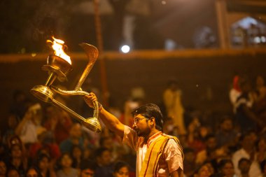 Varanasi, Uttar Pradesh, Hindistan - 21 Mart 2024: Ganga aarti, bir grup genç erkek rahip Assi Ghat 'ta geleneksel Hint ayinleri ile geleneksel elbise giyerek akşam üstü Ganga duası yapıyorlar..