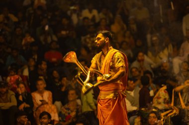 Varanasi, Uttar Pradesh, Hindistan - 21 Mart 2024: Ganga aarti, bir grup genç erkek rahip Assi Ghat 'ta geleneksel Hint ayinleri ile geleneksel elbise giyerek akşam üstü Ganga duası yapıyorlar..