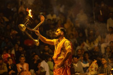 Varanasi, Uttar Pradesh, Hindistan - 21 Mart 2024: Ganga aarti, bir grup genç erkek rahip Assi Ghat 'ta geleneksel Hint ayinleri ile geleneksel elbise giyerek akşam üstü Ganga duası yapıyorlar..