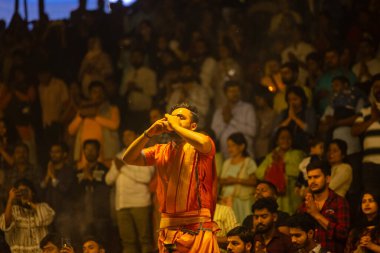 Varanasi, Uttar Pradesh, Hindistan - 21 Mart 2024: Ganga aarti, bir grup genç erkek rahip Assi Ghat 'ta geleneksel Hint ayinleri ile geleneksel elbise giyerek akşam üstü Ganga duası yapıyorlar..