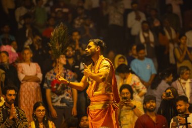 Varanasi, Uttar Pradesh, Hindistan - 21 Mart 2024: Ganga aarti, bir grup genç erkek rahip Assi Ghat 'ta geleneksel Hint ayinleri ile geleneksel elbise giyerek akşam üstü Ganga duası yapıyorlar..