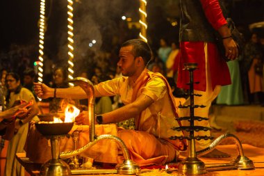 Varanasi, Uttar Pradesh, Hindistan - 21 Mart 2024: Ganga aarti, bir grup genç erkek rahip Assi Ghat 'ta geleneksel Hint ayinleri ile geleneksel elbise giyerek akşam üstü Ganga duası yapıyorlar..