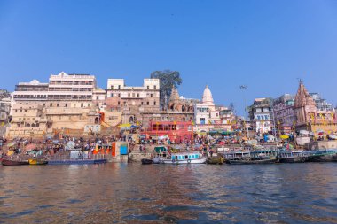 Varanasi, Uttar Pradesh, Hindistan - 22 Mart 2024: Varanasi 'deki nehir çetelerinin yakınlarındaki ghatların mimari görüşü. Ganga nehrinde yüzen tekneden binaların görüntüsü.