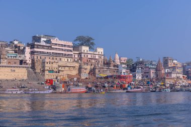 Varanasi, Uttar Pradesh, Hindistan - 22 Mart 2024: Varanasi 'deki nehir çetelerinin yakınlarındaki ghatların mimari görüşü. Ganga nehrinde yüzen tekneden binaların görüntüsü.