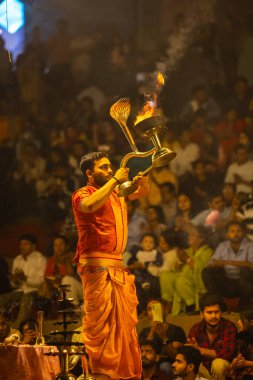 Varanasi, Uttar Pradesh, Hindistan - 21 Mart 2024: Ganga aarti, bir grup genç erkek rahip Assi Ghat 'ta geleneksel Hint ayinleri ile geleneksel elbise giyerek akşam üstü Ganga duası yapıyorlar..