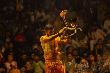 Varanasi, Uttar Pradesh, Hindistan - 21 Mart 2024: Ganga aarti, bir grup genç erkek rahip Assi Ghat 'ta geleneksel Hint ayinleri ile geleneksel elbise giyerek akşam üstü Ganga duası yapıyorlar..