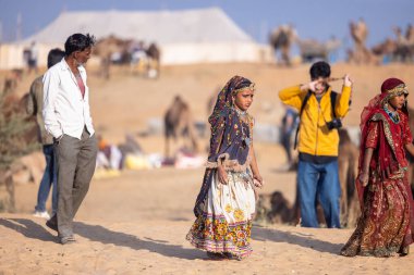 Puşkar, Rajasthan, Hindistan - 11 Kasım 2024: Kimliği belirsiz Hintli Rajasthani kadınlarından oluşan bir grup kış sabahı Pushkar Camel Panayırı 'nda dans ediyor.