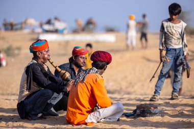 Puşkar, Rajasthan, Hindistan - 11 Kasım 2024: Çöldeki fuar alanında deve ticaret fuarı sırasında renkli türbanlı geleneksel beyaz giysili bir rajasthani erkeğinin portresi. 