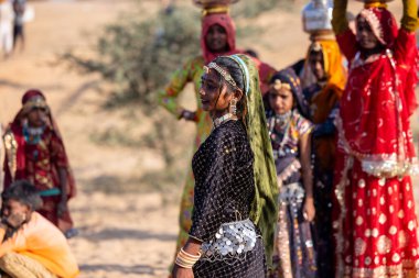 Puşkar, Rajasthan, Hindistan - 11 Kasım 2024: Kimliği belirsiz Hintli Rajasthani kadınlarından oluşan bir grup kış sabahı Pushkar Camel Panayırı 'nda dans ediyor.