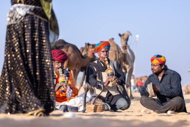 Puşkar, Rajasthan, Hindistan - 11 Kasım 2024: Çöldeki fuar alanında deve ticaret fuarı sırasında renkli türbanlı geleneksel beyaz giysili bir rajasthani erkeğinin portresi. 