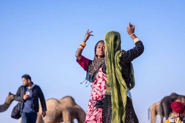 Puşkar, Rajasthan, Hindistan - 11 Kasım 2024: Kimliği belirsiz Hintli Rajasthani kadınlarından oluşan bir grup kış sabahı Pushkar Camel Panayırı 'nda dans ediyor.
