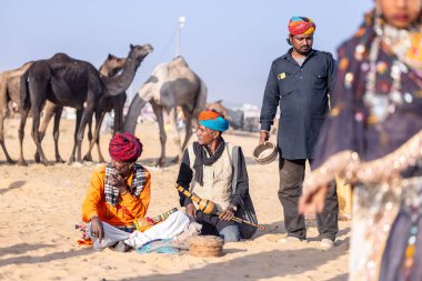 Puşkar, Rajasthan, Hindistan - 11 Kasım 2024: Çöldeki fuar alanında deve ticaret fuarı sırasında renkli türbanlı geleneksel beyaz giysili bir rajasthani erkeğinin portresi.