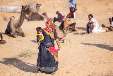 Puşkar, Rajasthan, Hindistan - 11 Kasım 2024: Kimliği belirlenemeyen Hintli Rajasthani kadınlarından oluşan bir grup kış sabahı Pushkar Camel Panayırı 'nda geleneksel renkli elbiseler giyiyor.