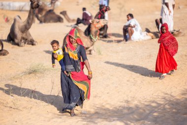 Puşkar, Rajasthan, Hindistan - 11 Kasım 2024: Kimliği belirlenemeyen Hintli Rajasthani kadınlarından oluşan bir grup kış sabahı Pushkar Camel Panayırı 'nda geleneksel renkli elbiseler giyiyor.