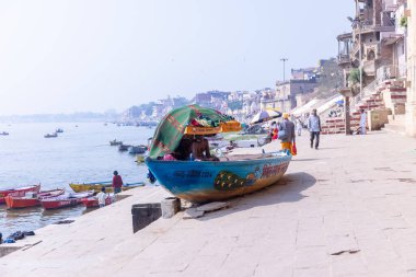 Varanasi, Uttar Pradesh, Hindistan - 22 Mart 2024: Varanasi 'deki çetelerin yakınındaki assi ghat' ta şemsiye altında oturan geleneksel bir Brahman rahibinin portresi.