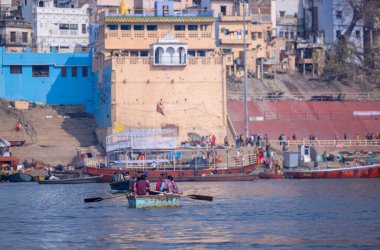 Varanasi, Uttar Pradesh, Hindistan - 22 Mart 2024: Kimliği belirsiz turist ve müritler nehir gangasında ahşap botlara binip tapınılacak antik tapınakları ve binaları görmeye gidiyorlar.