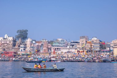 Varanasi, Uttar Pradesh, Hindistan - 22 Mart 2024: Kimliği belirsiz turist ve müritler nehir gangasında ahşap botlara binip tapınılacak antik tapınakları ve binaları görmeye gidiyorlar.