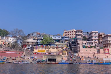 Varanasi, Uttar Pradesh, Hindistan - 22 Mart 2024: Varanasi 'deki nehir çetelerinin yakınındaki ghatların mimari görüşü ve tapınakları. Ganga nehrinde yüzen tekneden binaların görüntüsü.